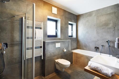 uma casa de banho com um WC, um lavatório e um chuveiro em Kristall Plaza em Niederau