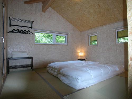 Un dormitorio con una gran cama blanca con dos ventanas. en Chalet Hinata Hakuba, en Hakuba