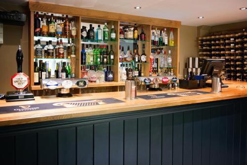 a bar with a lot of bottles of alcohol at The George Great Oxendon in East Farndon
