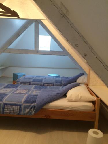 a bed with a blue comforter in a attic at La Maison Bellevue in Saint-Efflam
