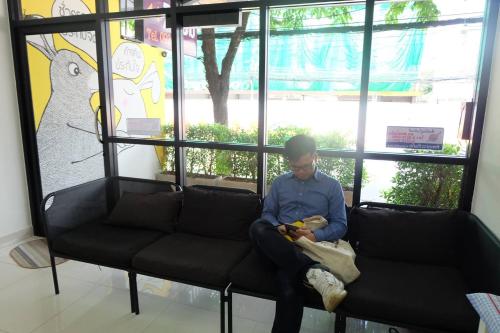 un uomo seduto su un divano davanti a una finestra di Rabbit Room a Bangkok