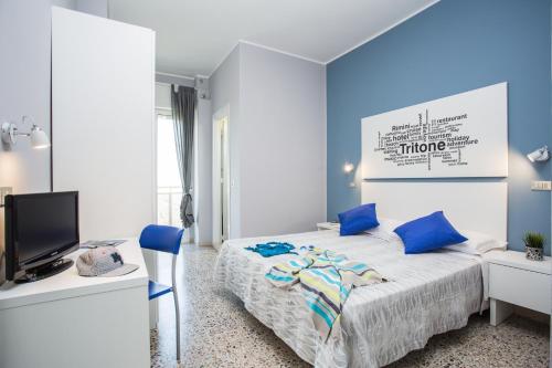a bedroom with blue walls and a bed with blue pillows at Hotel Tritone Rimini in Rimini