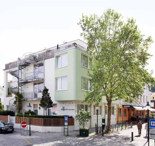 a green building with a tree in front of it at Hotel Babenbergerhof in Mödling