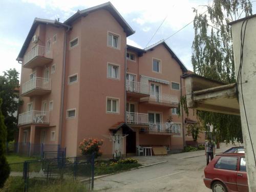 ein großes rosafarbenes Gebäude mit Balkon auf einer Straße in der Unterkunft Apartments Petkovic in Sokobanja