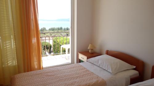 a bedroom with a bed and a large window at Apartmani Pilić Ljiljana in Brodarica