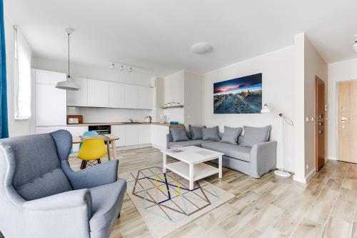 a living room with two couches and a kitchen at INA Rent - Tre Mare Apartamenty in Gdańsk