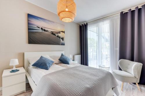 a bedroom with a bed and a chair and a window at INA Rent - Tre Mare Apartamenty in Gdańsk