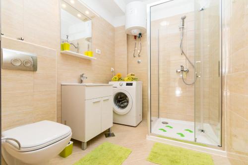 a bathroom with a shower toilet and a washing machine at APARTMENT JURAŠIN in Kaštela