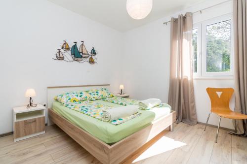 a bedroom with a bed and a window and a chair at APARTMENT JURAŠIN in Kaštela