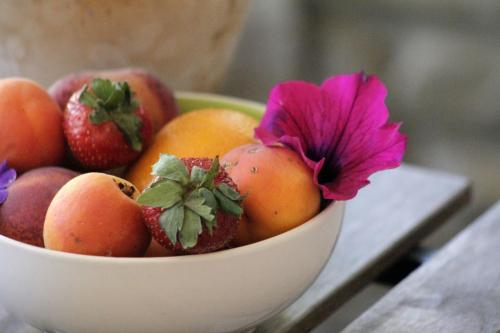 a bowl of fruit with a pink flower in it at B&B Villa Dalegno in Temù