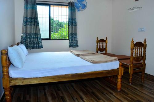 a bedroom with a bed with two chairs and a window at Hills View Stay in Māvingundi