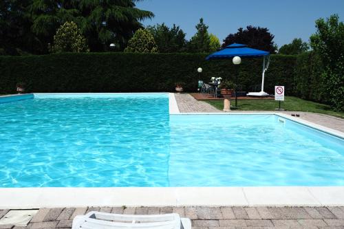 a pool with two chairs and an umbrella at Hotel Spresiano in Spresiano