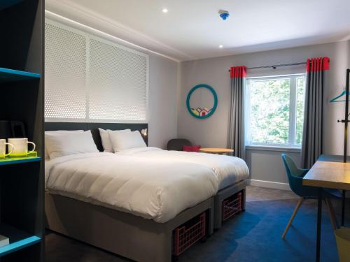 a bedroom with a bed and a desk and a window at Lodge at Solent in Fareham