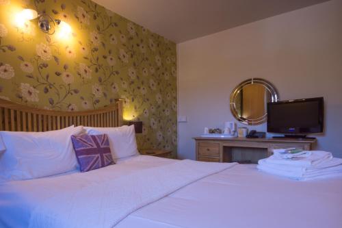 a bedroom with a white bed with a mirror and a tv at Yorkshire Bridge Inn in Bamford