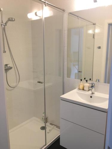a white bathroom with a shower and a sink at Apartament Słoneczny Dwie Sosny in Ustronie Morskie
