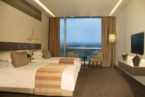 a hotel room with two beds and a large window at Erbil Arjaan by Rotana in Erbil