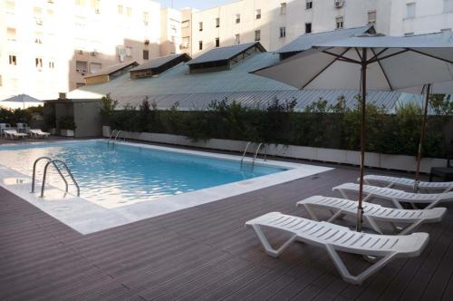 una piscina con due sedie e un ombrellone di Apartamento Boulevard Juan Bravo a Madrid