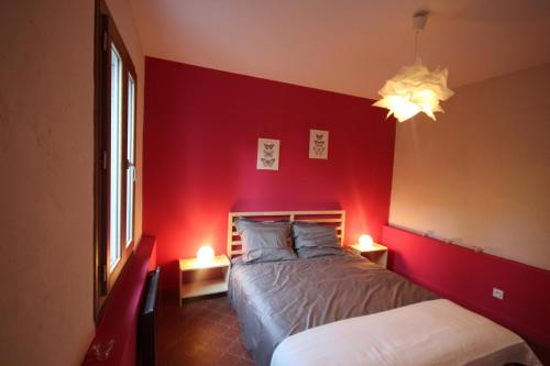 - une chambre dotée d'un mur rouge avec un lit et deux lampes dans l'établissement Le Joli Nid, à Toulouse