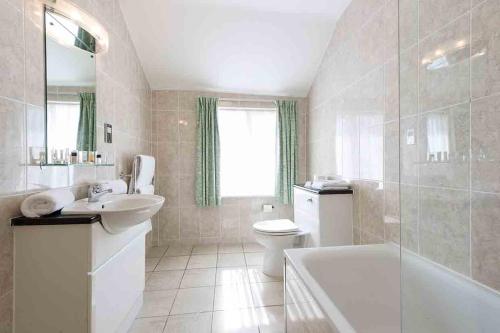 a bathroom with a tub and a sink and a toilet at The Rutland Hotel in Douglas