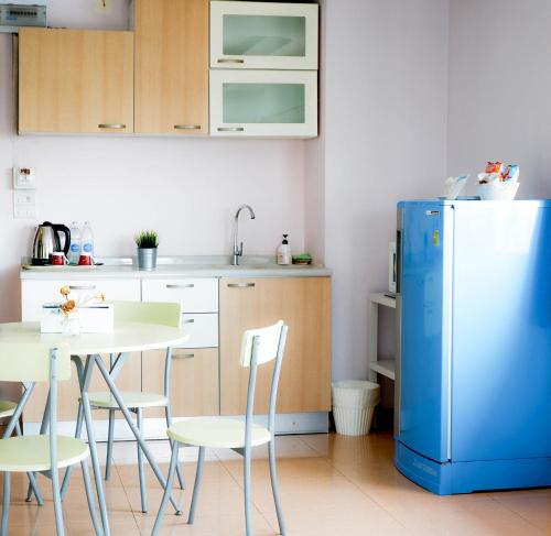 a kitchen with a table and a blue refrigerator at Ingnaam Hotel in Ban Talat Rangsit