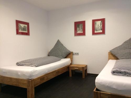 MorschenにあるFeWo Bettenhausenのベッド2台が備わるお部屋で、壁に絵が飾られています。
