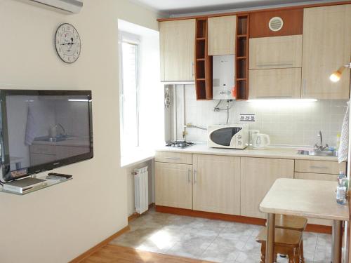 a kitchen with wooden cabinets and a tv on the wall at Apartment on Nimanska 5 in Kyiv
