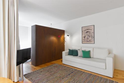 a living room with a white couch and a television at Casas do Rivoli in Porto