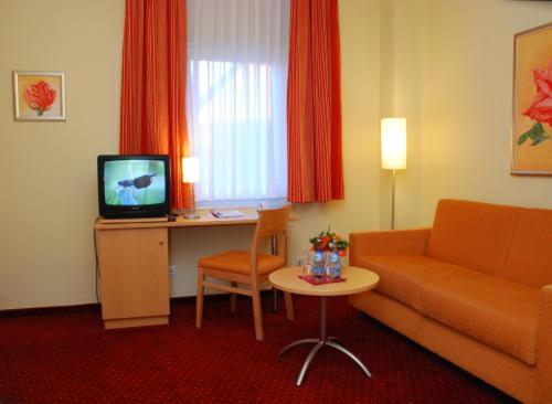 Habitación de hotel con sofá, mesa y TV en Hotel Tivoli, en Osterholz-Scharmbeck