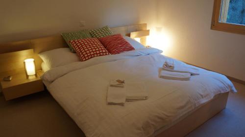 a bedroom with a large white bed with towels on it at Roossi-Huus 2 in Wengen