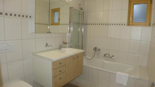 a bathroom with a sink and a tub and a toilet at Roossi-Huus 2 in Wengen