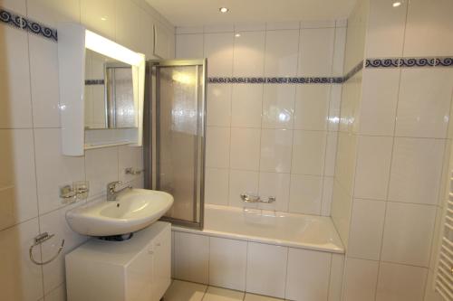 y baño blanco con lavabo y ducha. en Rosat 25, en Château-d'Oex