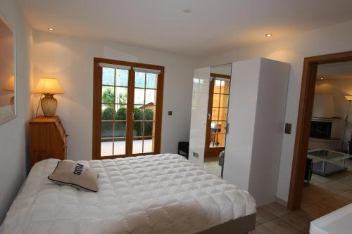 Un dormitorio con una gran cama blanca y una ventana. en Rosat 25, en Château-d'Oex