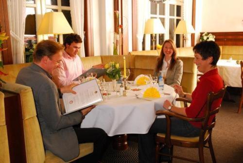 a group of people sitting around a table in a restaurant at Hotel Tivoli in Osterholz-Scharmbeck