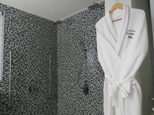 a white robe hanging in a bathroom with a shower at Nieuwehuyz in Prince Albert