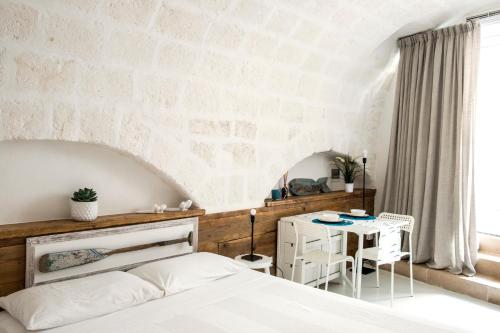 sypialnia z białym łóżkiem i stołem w obiekcie Borgo Albergo Capozzi 37 w mieście Monopoli