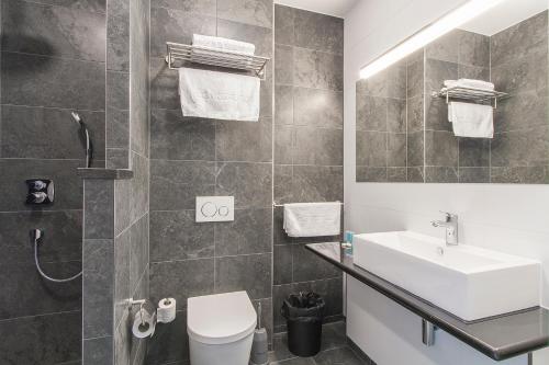 La salle de bains est pourvue d'un lavabo, de toilettes et d'un miroir. dans l'établissement Bastion Hotel Eindhoven Waalre, à Eindhoven