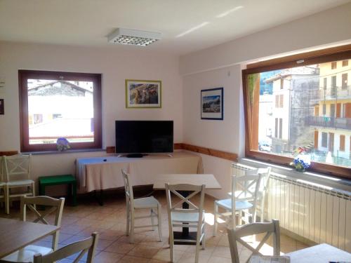 a dining room with a table and chairs and a tv at Spazio Gran Paradiso Guest House in Alpette