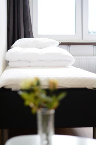 two white pillows and a vase with a plant on a table at Alkoven Logi in Ullared