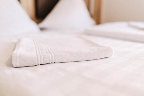 a pile of white towels on a bed at Gasthof Metzgerei Linsmeier in Iggensbach