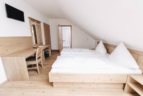 two beds in a room with a desk and a table at Gasthof Metzgerei Linsmeier in Iggensbach
