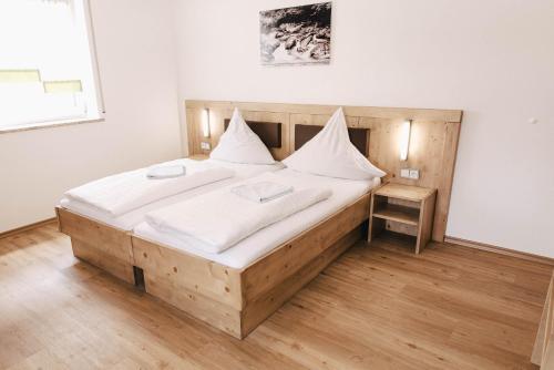 um quarto com uma grande cama de madeira com lençóis brancos em Gasthof Metzgerei Linsmeier em Iggensbach
