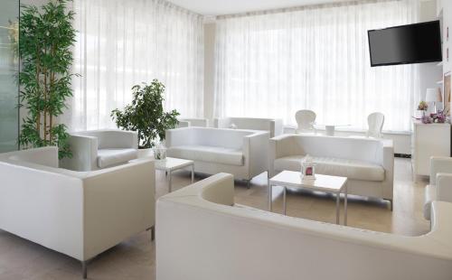 a living room with white furniture and a flat screen tv at Hotel Radar in Rimini