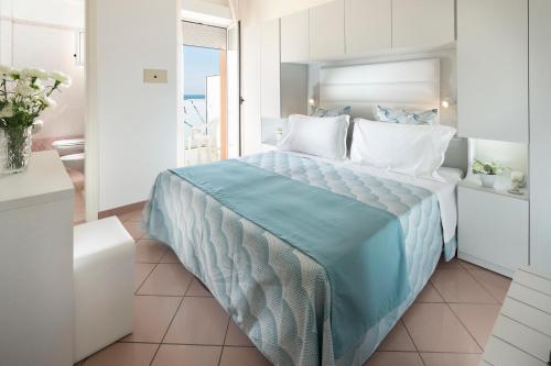 a bedroom with a large bed with blue sheets and pillows at Hotel Radar in Rimini