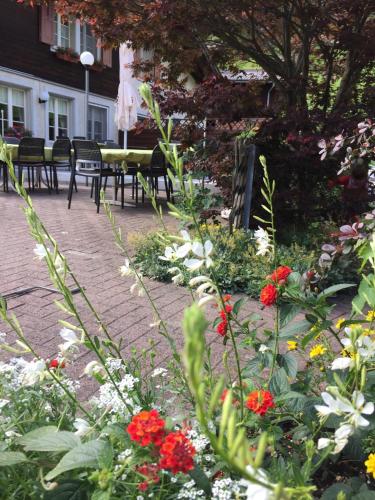 a garden with red and white flowers and tables and chairs at Gästehaus Schäfli in Intschi