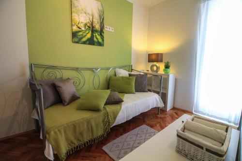 Un dormitorio con una cama con paredes verdes y un sofá en Apartments Lavanda, en Primošten