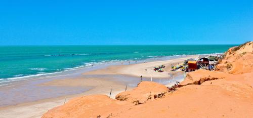 a beach with a group of people and the ocean at Hotel & Pousada Tatajuba in Canoa Quebrada