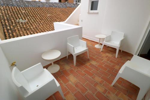 a room with white chairs and tables on a brick floor at Guest House do Largo in Faro