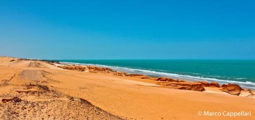 a sandy beach with the ocean in the background at Hotel & Pousada Tatajuba in Canoa Quebrada