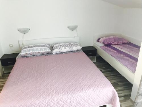 特孔的住宿－Apartmani Bruna，配有粉红色和紫色床单的客房内的两张床