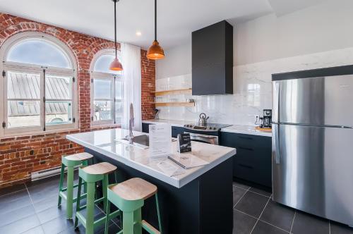 a kitchen with a counter and a refrigerator at Les Lofts du Trésor - Par Les Lofts Vieux-Québec in Quebec City